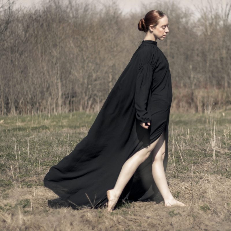 Woman in a field wearing black organic dresses
