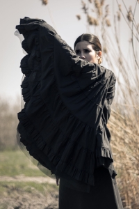 Woman in a field wearing black cape