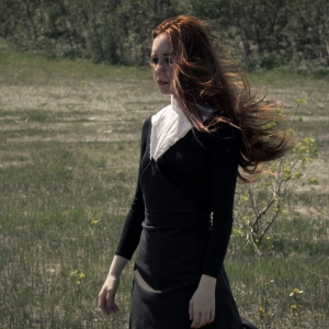 Woman in a field wearing black organic dress with white collar