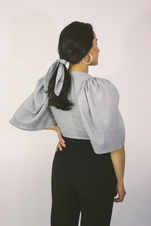 Woman wearing grey linen wrap top with puff sleeves