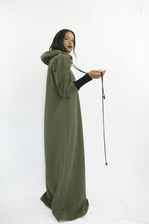 Woman wearing long forest green dress in organic cotton with gathered ruff collar and draw strings, puffy sleeves and long rib cuffs