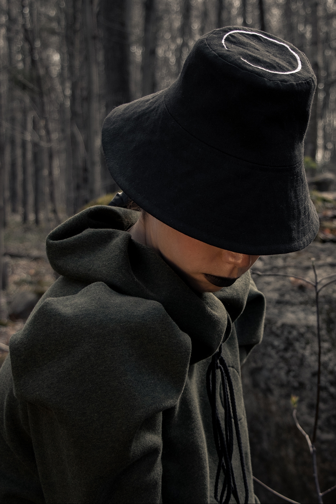Woman wearing black bucket hat with logo in the woods