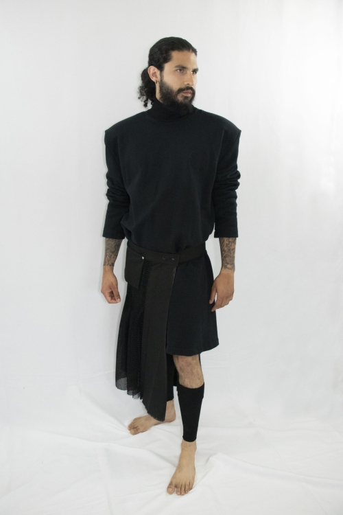 Man wearing black assymetric pleated kilt with front pocket and snap-belt made from zero waste and organic materials