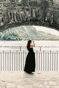 Woman wearing long black dress with open front slit in a lakefront castle