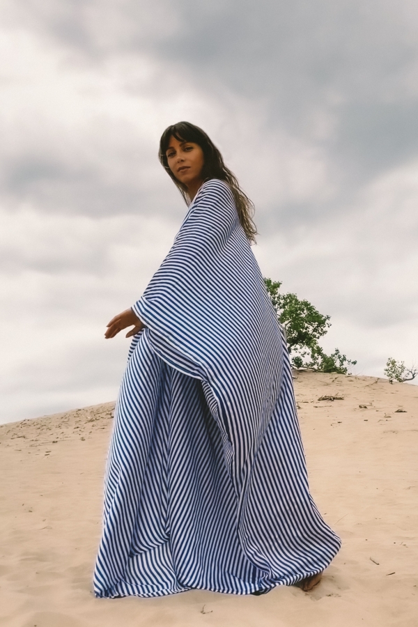 Woman wearing long blue kaftan goddess dress on the sand dunes